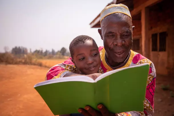 Grand père lisant un livre à son petit-fis